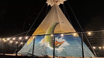 A large conical tent with a fish design on the sides, supported by a metal frame and string lights.