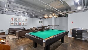 Ein Billardraum mit Billardtisch, Sofas und gerahmten Bildern an der Wand.