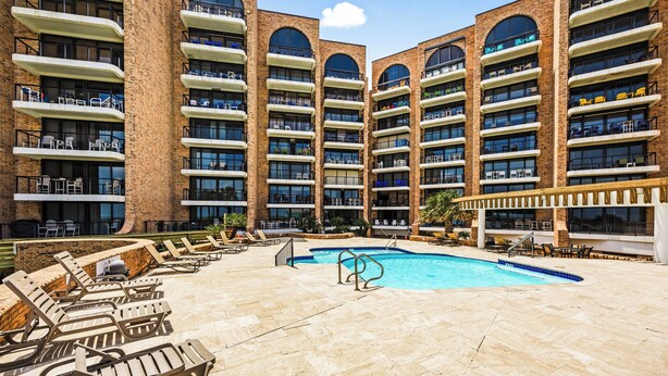 Un hotel con varios balcones, piscina y tumbonas.