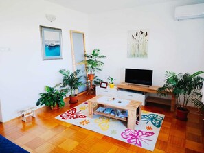 A living room with a TV, wooden furniture, potted plants, and artwork on the walls. - Spacious, cozy 2-bedroom apartment with AC,balcony,parking in charming Hreljin (Hreljin)