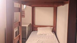 A bunk bed with a lower bunk and a single bed. There is a small shelf unit to the left and a wall-mounted heater below the lower bunk. - Boaventura  (Unaí)