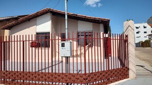 A building with a red metal fence, a white brick wall, and a tiled roof. - Boaventura  (Unaí)