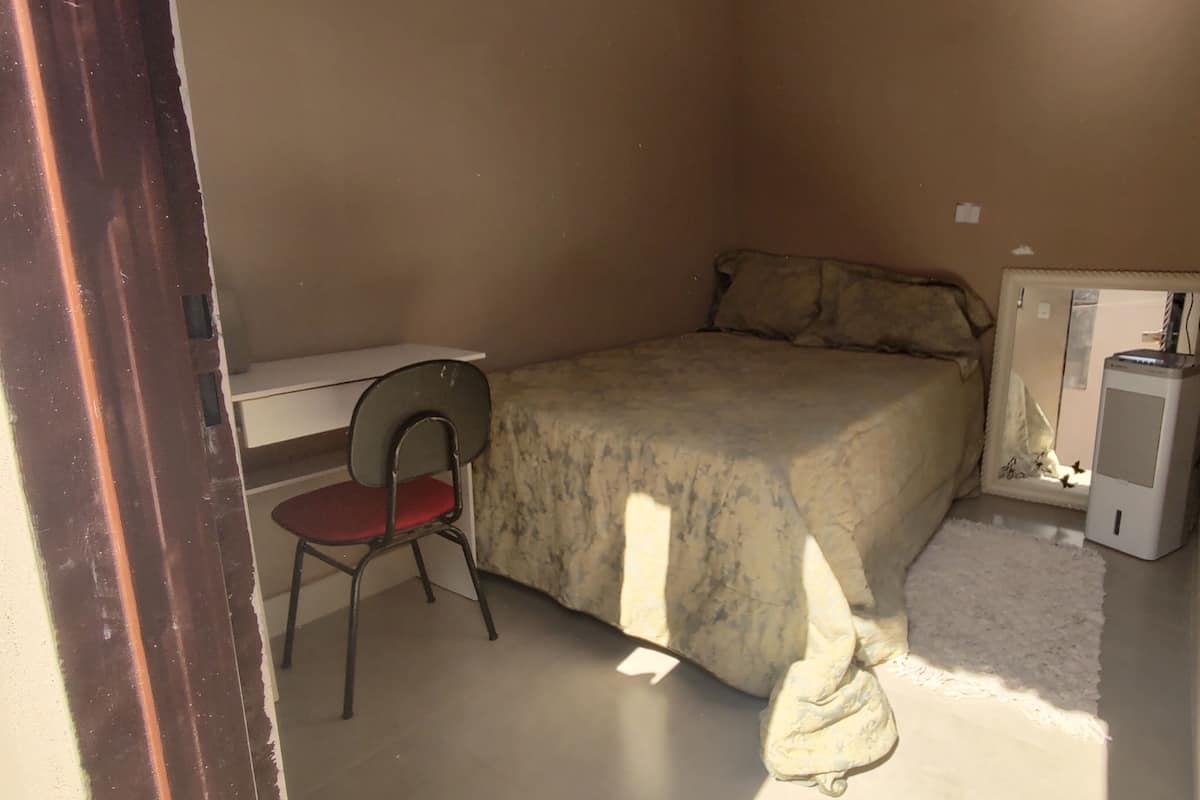A small bedroom with a bed, a chair, and a desk.