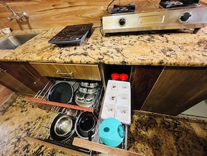 Uma cozinha com bancada de granito, forno embutido, cafeteira e organizador de gaveta com panelas e frigideiras.