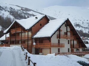 Ein Chalet-ähnliches Gebäude mit mehreren Balkonen, umgeben von schneebedeckten Bergen.