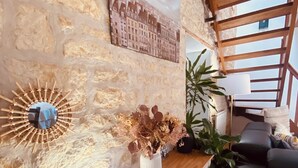 Um console de madeira com um vaso de flores secas, um espelho fixado na parede e um quadro emoldurado.