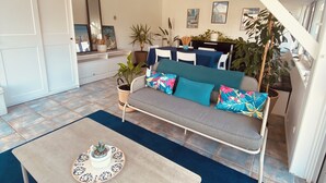 Uma sala de estar acolhedora com um sofá, uma mesa de centro e plantas em vasos.