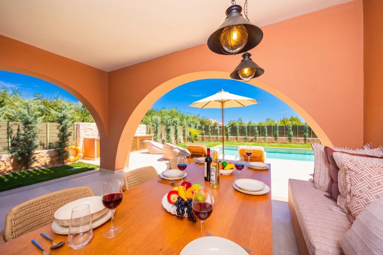Un espace extérieur aménagé pour les repas, avec vue sur la piscine, comprenant une table en bois, des chaises et un canapé.
