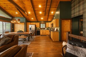 A spacious kitchen with wooden cabinets, a dining area with leather chairs, and a large wooden ceiling.