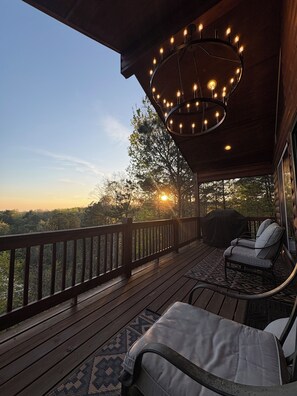 A wooden deck with a railing, a hanging light fixture, and a chair. - Retreat•50 Acres•Mtn Views• Hot Tub•Fire Pit•Sleeps 10•Game Room•Carters Lake (Ellijay)