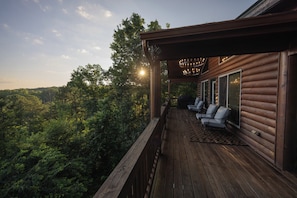 A wooden deck with outdoor seating and a view of a forested area. - Retreat•50 Acres•Mtn Views• Hot Tub•Fire Pit•Sleeps 10•Game & Media Room•Ellijay (Ellijay)