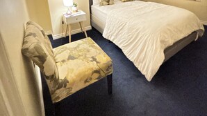 Une chambre à coucher avec un lit, une chaise, un bureau et un miroir.