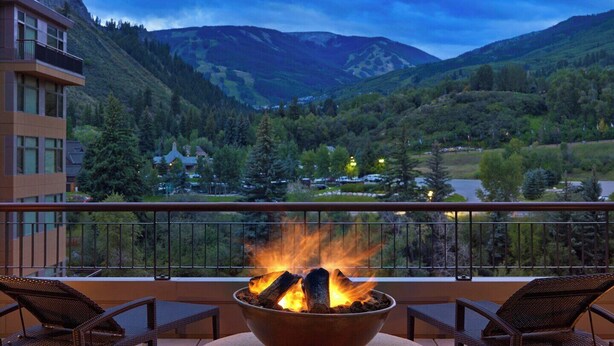 A balcony with a fire pit, overlooking a mountainous landscape with a view of a valley and a building in the background. - Spacious, luxury villa at 5-star Westin Riverfront. Best pool, spa, fitness,etc! (Avon)