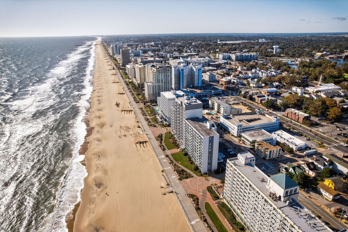 Ein Luftbild einer Küstenstadt mit einem langen Sandstrand, Hochhäusern und einer Mischung aus Wohn- und Geschäftsbereichen.