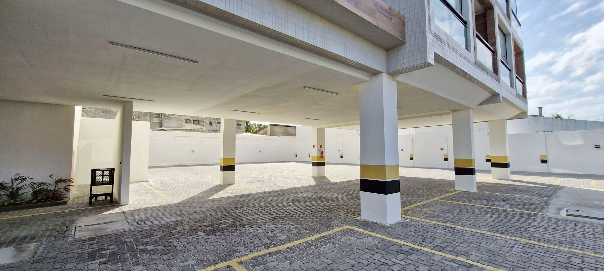 Un área de estacionamiento con pavimento de adoquines y pilares blancos con franjas amarillas y negras.