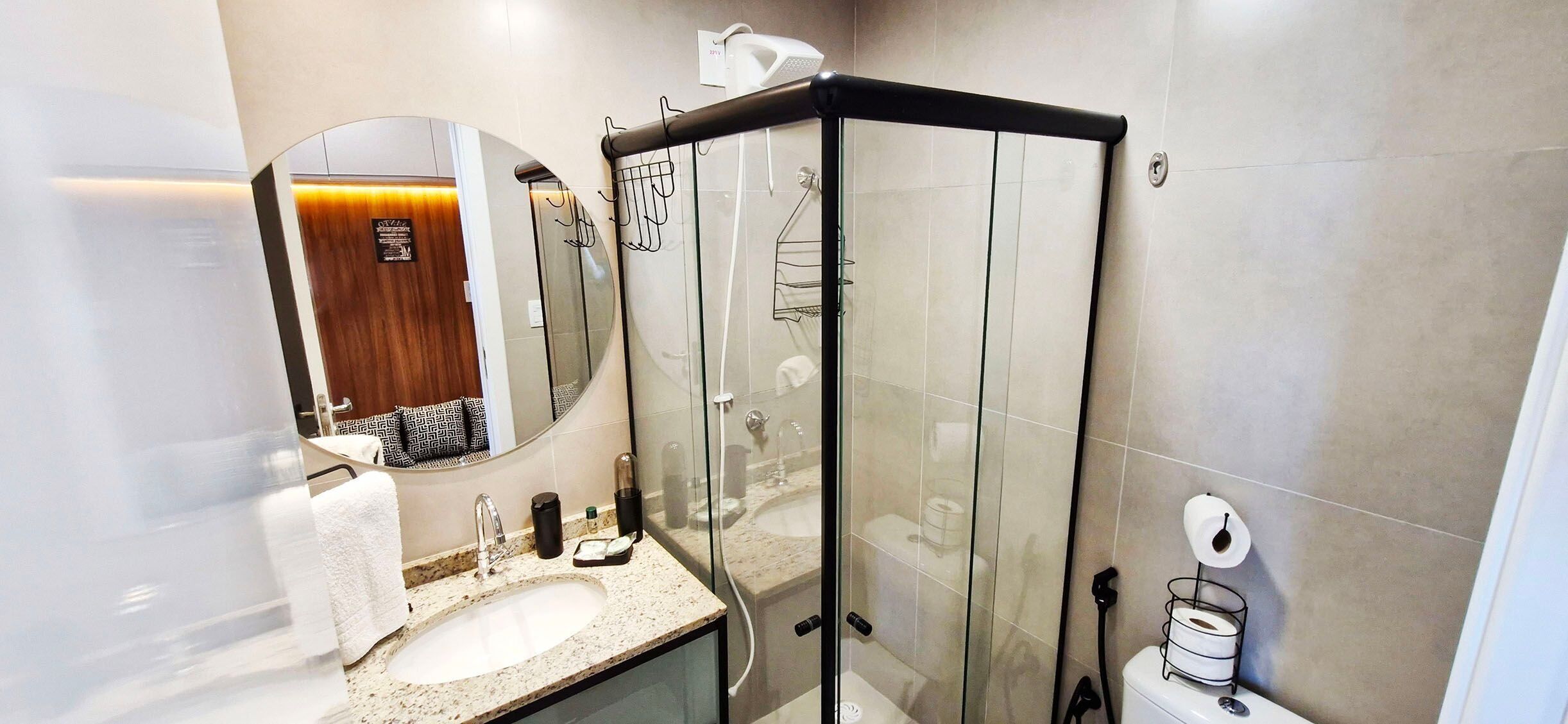 A modern bathroom with a glass-enclosed shower, a sink with a mirror, and a toilet.