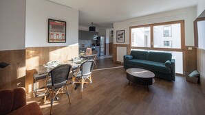 A modern living room with a dining area, a sofa, and a kitchen in the background. - Three trips, one single stay on the gate of Paris ! You'll love it. (Bagneux)