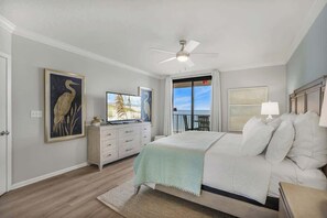 Een slaapkamer met een bed, een plafondventilator, een dressoir, een televisietoestel en kunst aan de muur.