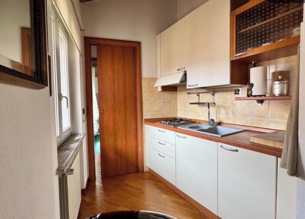 Une cuisine de taille réduite avec des meubles blancs, un plan de travail en bois et une cuisinière intégrée.