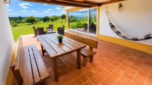 Une table et des bancs en bois sur une terrasse offrant une vue sur un paysage verdoyant.