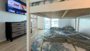 A bedroom with a bunk bed, a TV mounted on the wall, a dresser, and a view of the outdoors. - Bayfront w-docks & fish 3 Patios  Prime Location (South Padre Island)