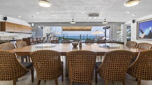 A spacious dining area with a large wooden table and wicker chairs, overlooking a scenic ocean view. - Resort-Style Villa w/ Private Padel & Infinity Pool (Bucerías)