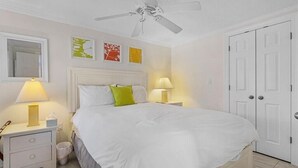 A bedroom with a large bed, two bedside lamps, a ceiling fan, and a white door. - The Cozy 1 Bed / 1 Bath Duplex Near Vanderbilt Beach (Naples)