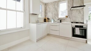 Et moderne køkken med hvide skabe, et marmor-bagsplade og en indbygget ovn.
