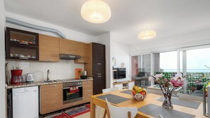 A modern kitchen with wooden cabinets, a dishwasher, and a dining area with a table and chairs.