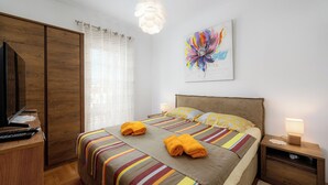 A bedroom with a bed, a desk, a wardrobe, a nightstand, and a painting.