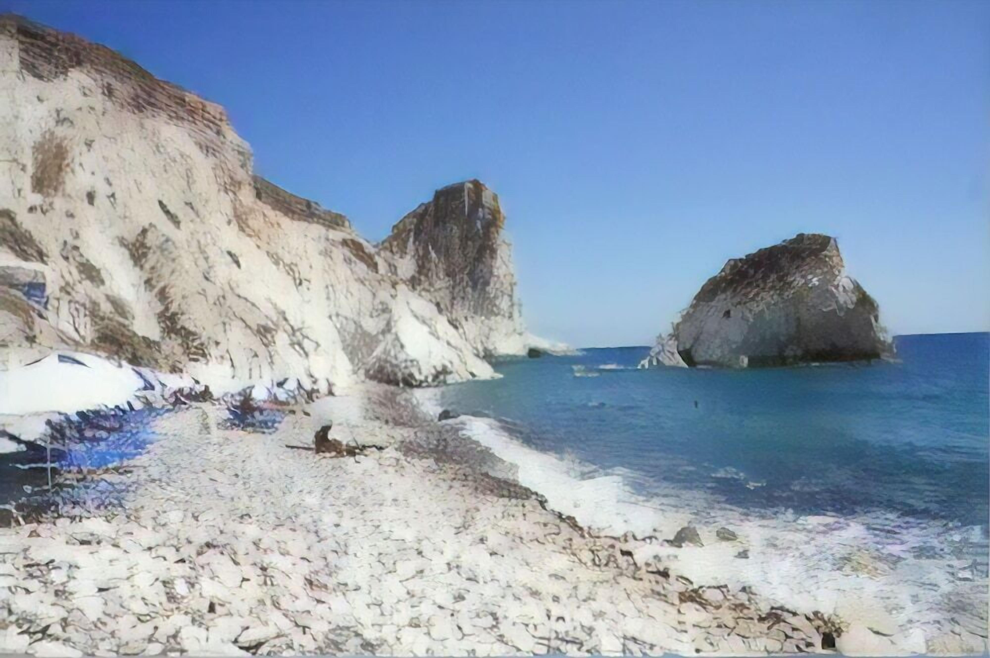 Ein felsiger Strand mit klarem, blauem Wasser und großen Felsen.