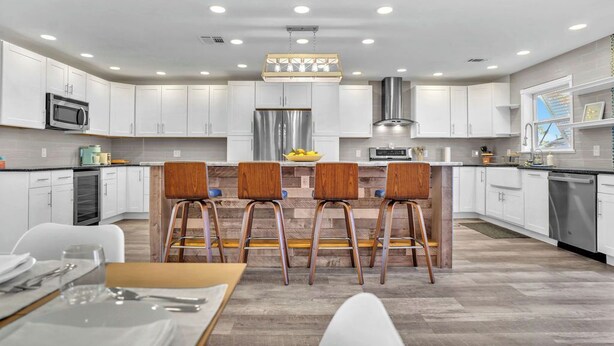 A modern kitchen with white cabinets, stainless steel appliances, and a central island with bar stools.