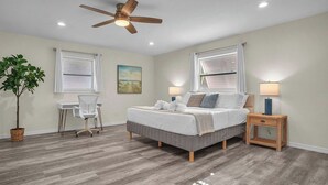 A bedroom with a bed, desk, chair, and a ceiling fan.