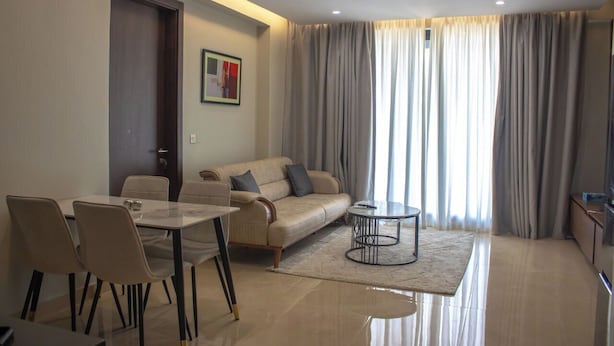 A modern living room with a sofa, dining table, chairs, and a coffee table. - The Bravia Residency by Cozy (Accra)