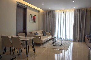 A modern living room with a sofa, dining table, chairs, and a coffee table. - The Bravia Residency by Cozy (Accra)