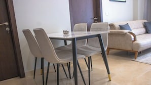 A dining area with a glass table and four chairs, a sofa, and a door. - The Bravia Residency by Cozy (Accra)