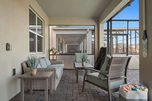 Eine überdachte Terrasse mit Korbmöbeln, einem Tisch und Stühlen.