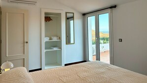 Een slaapkamer met een bed, een kledingkast, een spiegel en een glazen schuifdeur die leidt naar een balkon.