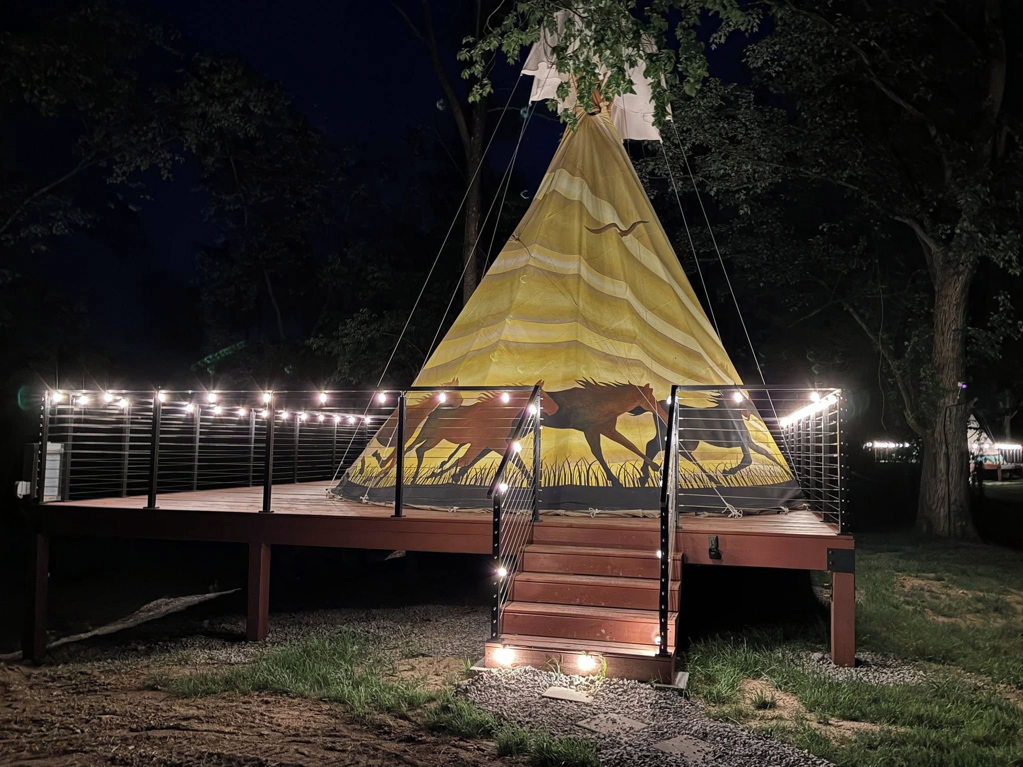 A tent-like structure with a horse silhouette, surrounded by a metal railing and lights.