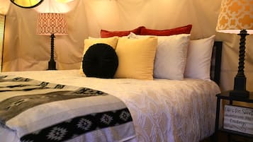 A bed with a patterned bedspread, multiple pillows, and two lamps with patterned shades.