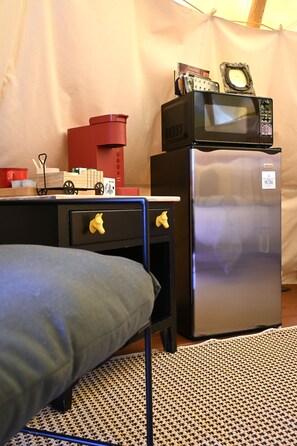 Uma cozinha compacta equipada com geladeira, micro-ondas e cafeteira.