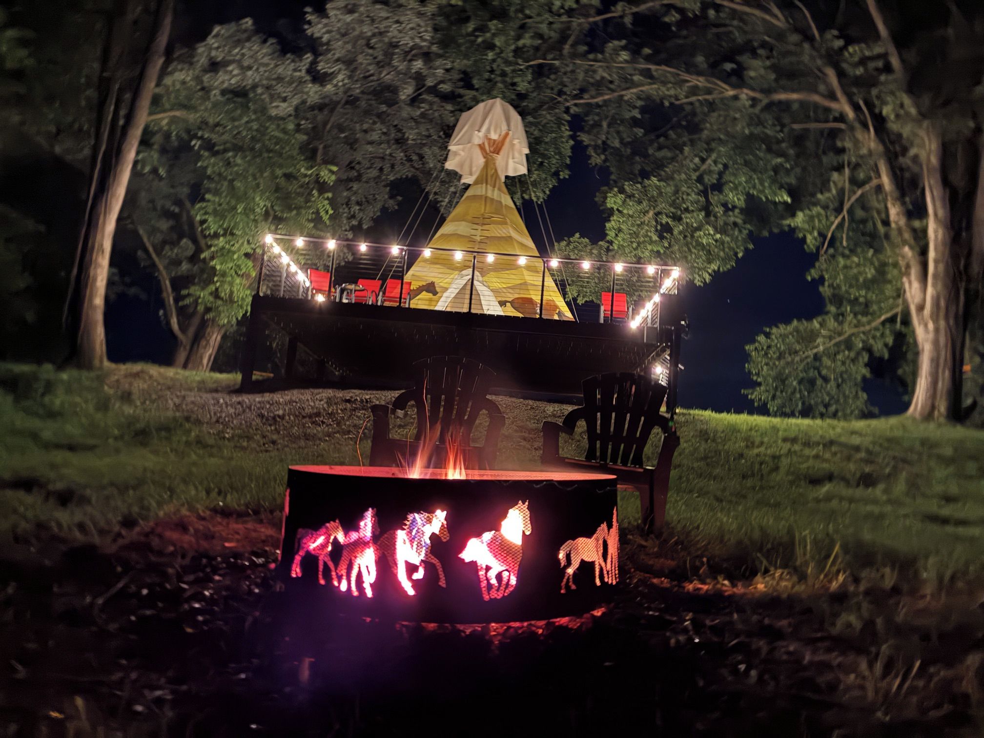 A covered outdoor seating area with a fire pit and illuminated horse silhouettes.