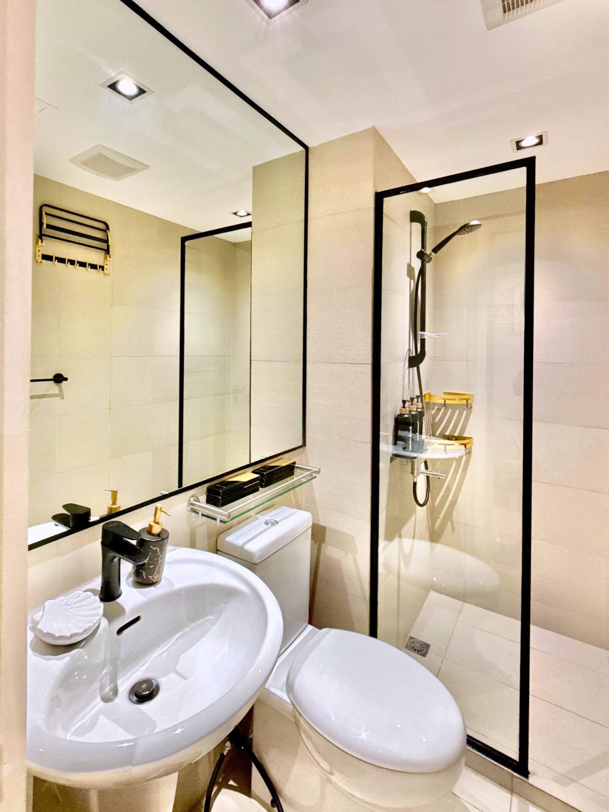 A modern bathroom with a white sink, toilet, and glass-enclosed shower.