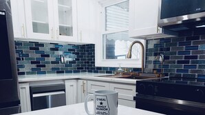 Una cocina moderna con armarios blancos, salpicadero azul y negro, y una estufa de acero inoxidable.