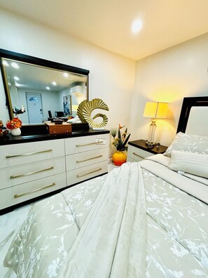 A bedroom with a bed, a dresser, a mirror, a lamp, and decorative items.