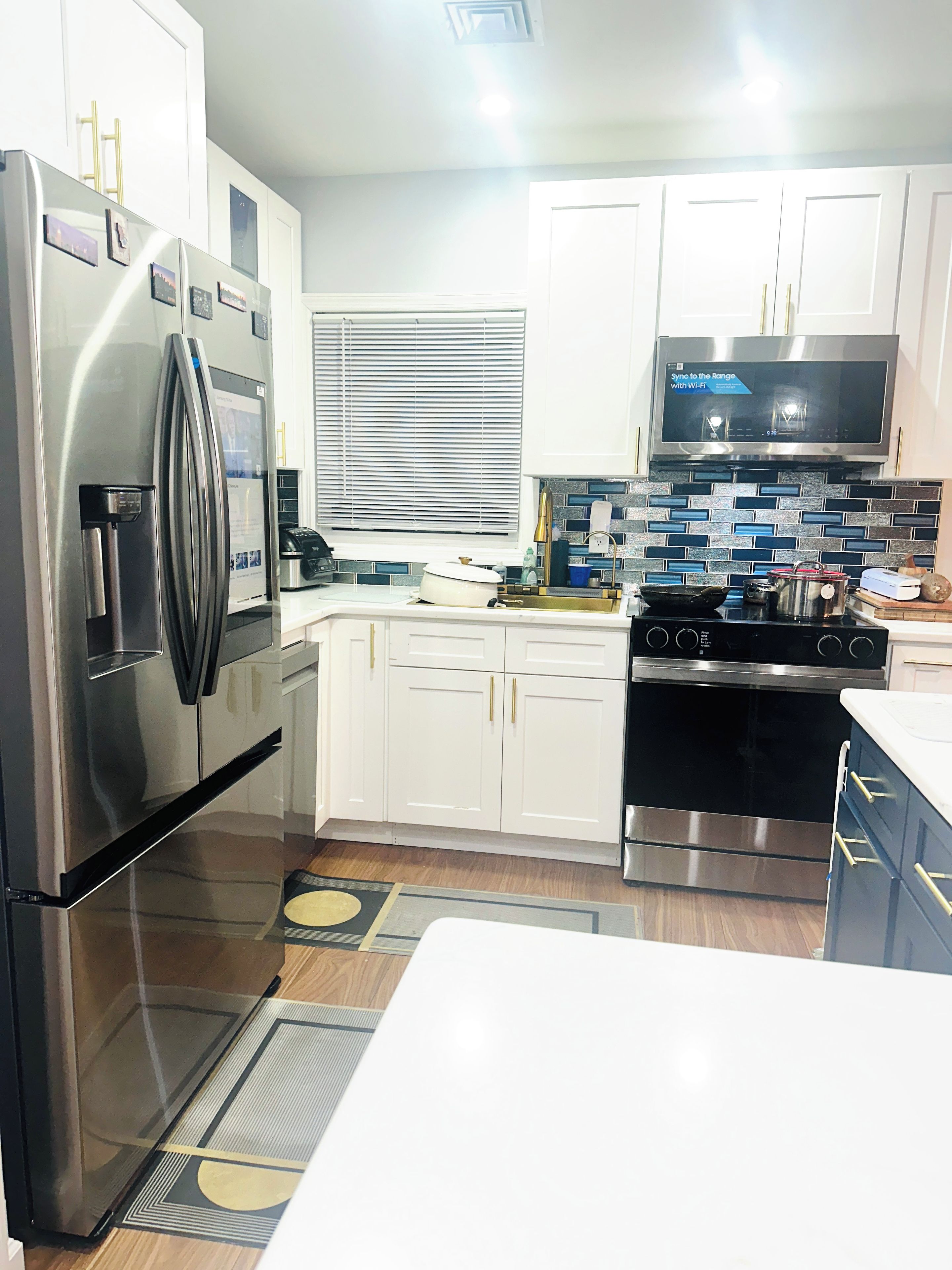 A modern kitchen with stainless steel appliances, white cabinetry, and a black stove.