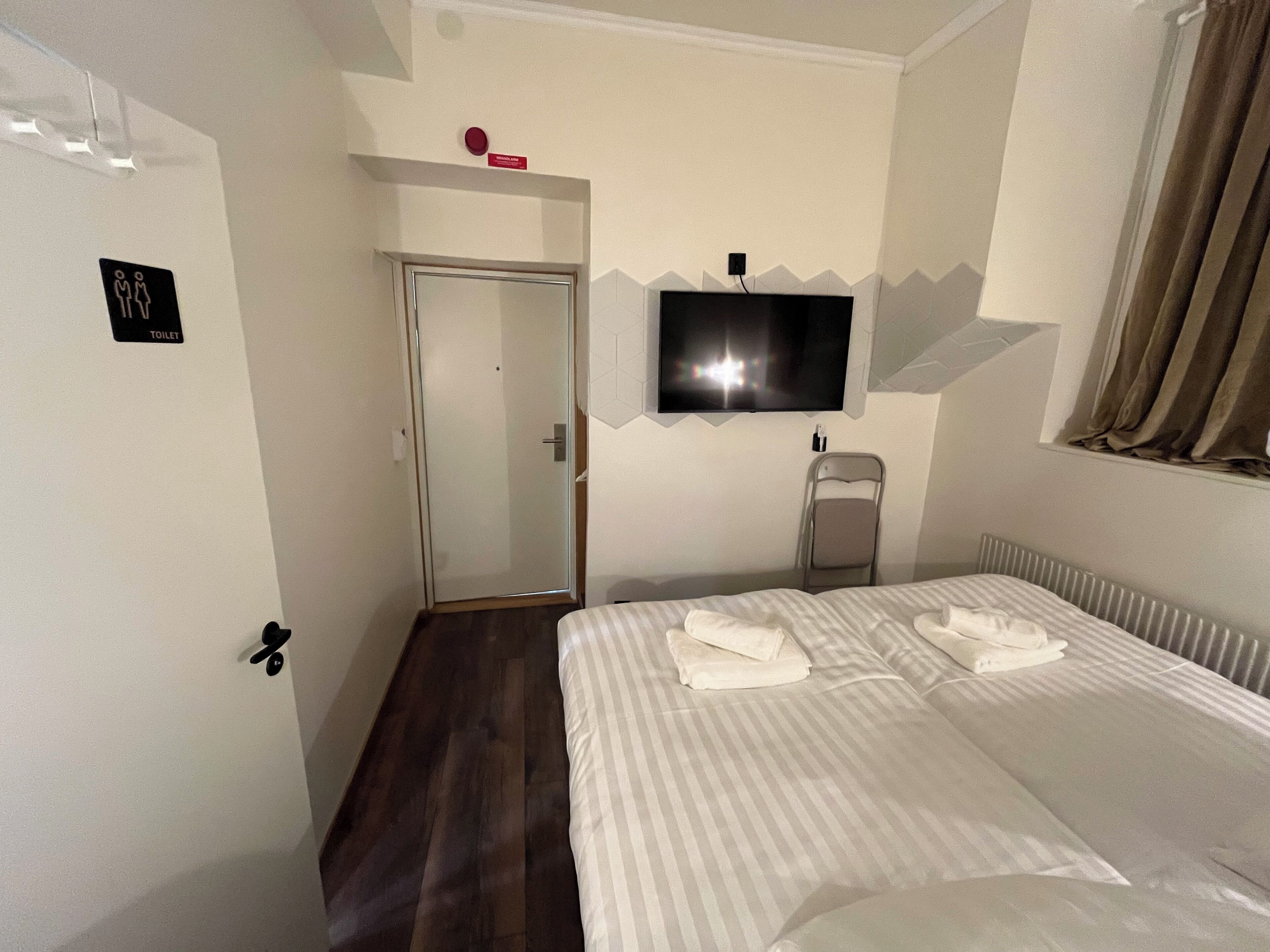 A hotel room with a bed, a TV, a toilet, and a shower.