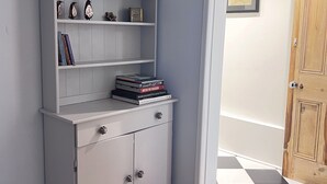 Una habitación de esquina con un armario blanco contra la pared, una puerta de madera y un piso a cuadros.