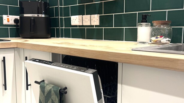 Una cocina con una cafetera Bosch, un escurreplatos y un colgador para ollas.