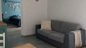 Een moderne woonkamer met een grijze bank, een houten tafel en een rond geweven vloerkleed.